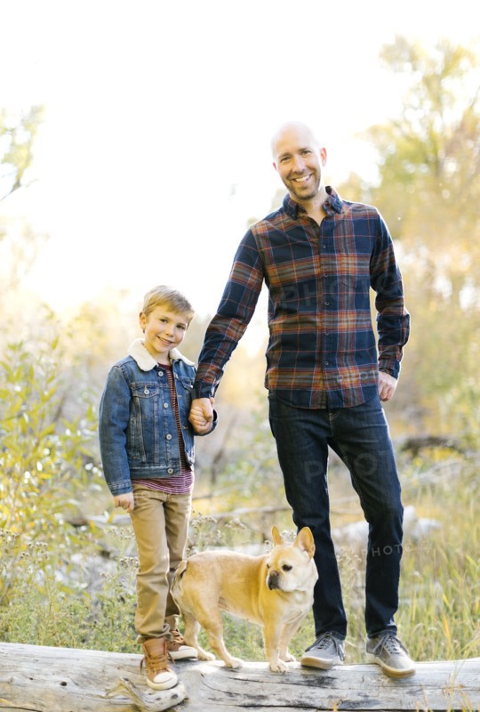 Father and son with pet French bulldog on fallen tree