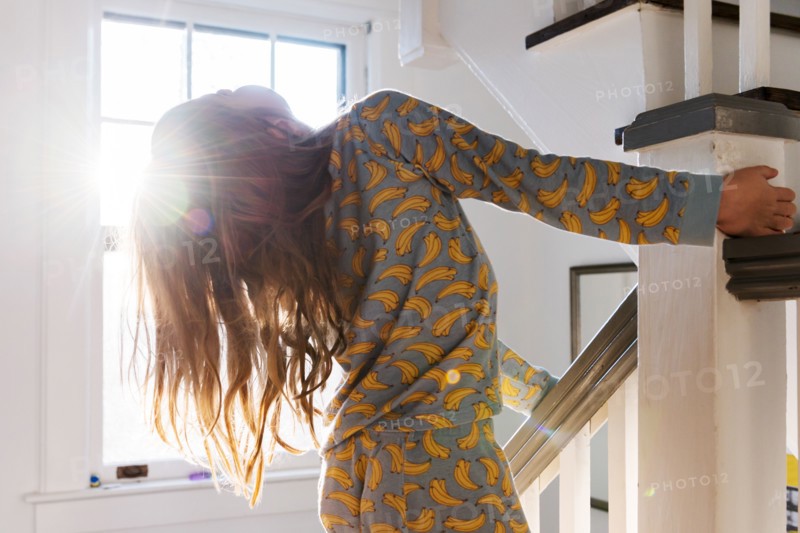 Girl in pajamas playing on banister