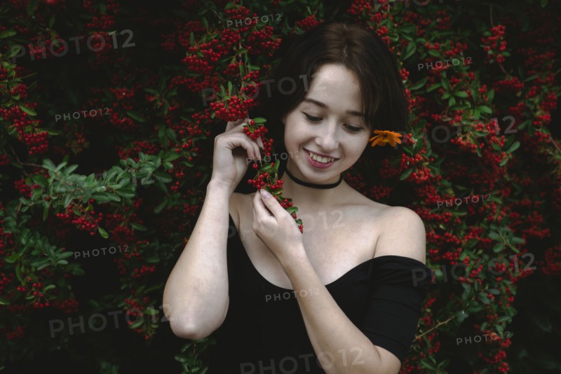 young woman standing by bush with red berries