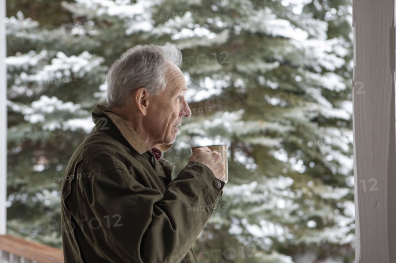 Senior man with cup of coffee by snowy pine tree