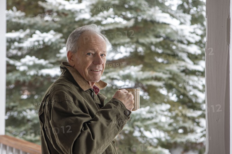 Senior man with cup of coffee by snowy pine tree