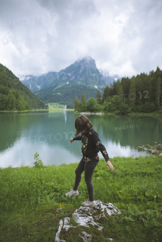 young woman balancing on rock by lake