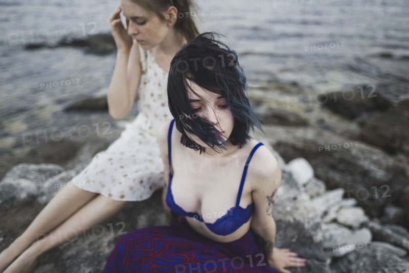 young women sitting together on beach