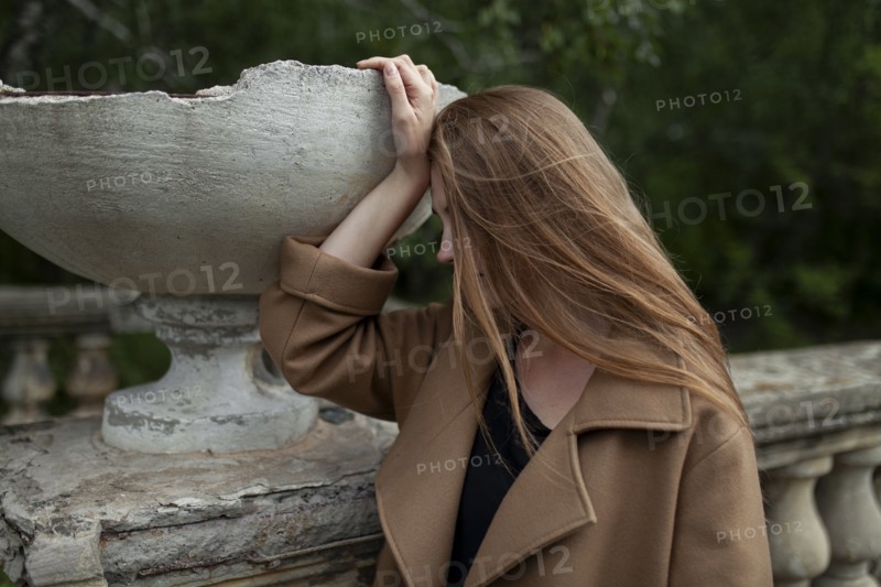 young woman holding broken flower pot on stone banister