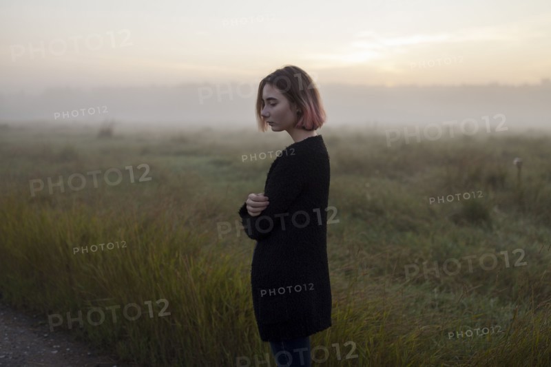 young woman in field at sunset