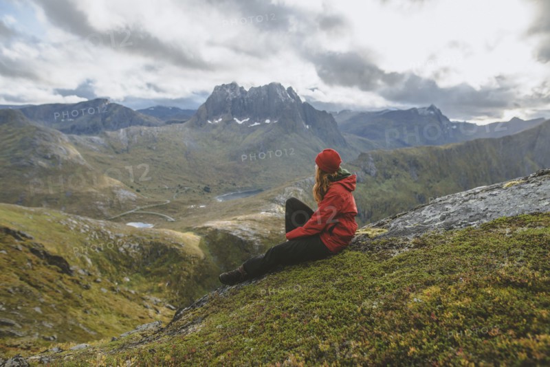 young woman in red jacket sitting on mountain