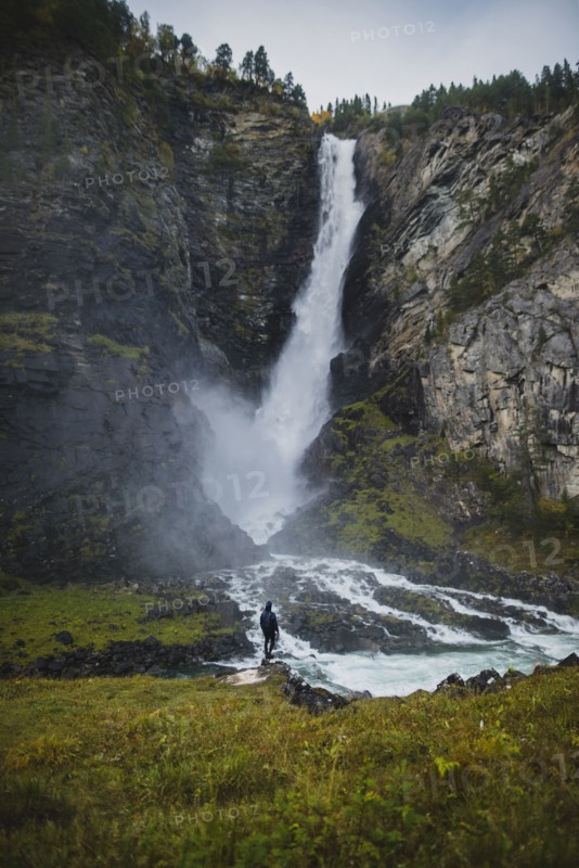 young man standing by waterfall