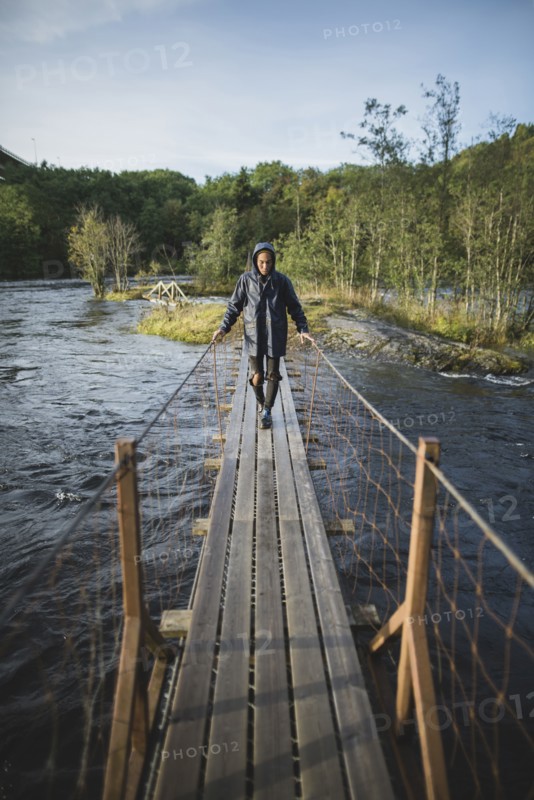 young man walking over wooden bridge
