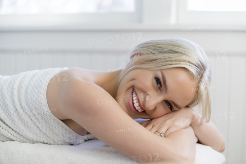 Portrait of young woman with toothy smiling on massage table