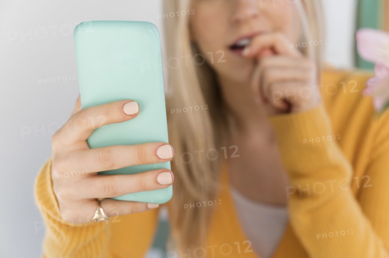 Woman holding smartphone and biting nails