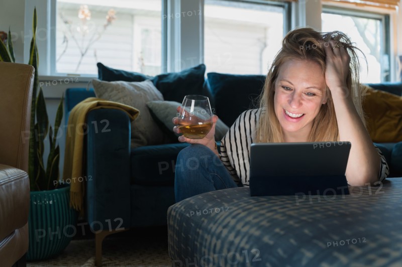 Relaxed woman with wine looking at tablet at home