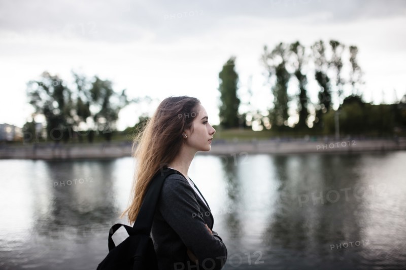 Woman walking near lake in cloudy weather