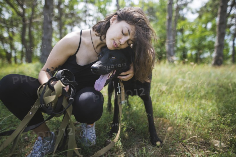 Young woman hugging dog from animal shelter in forest
