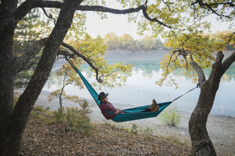 Italy, Man lying in hammock near lake