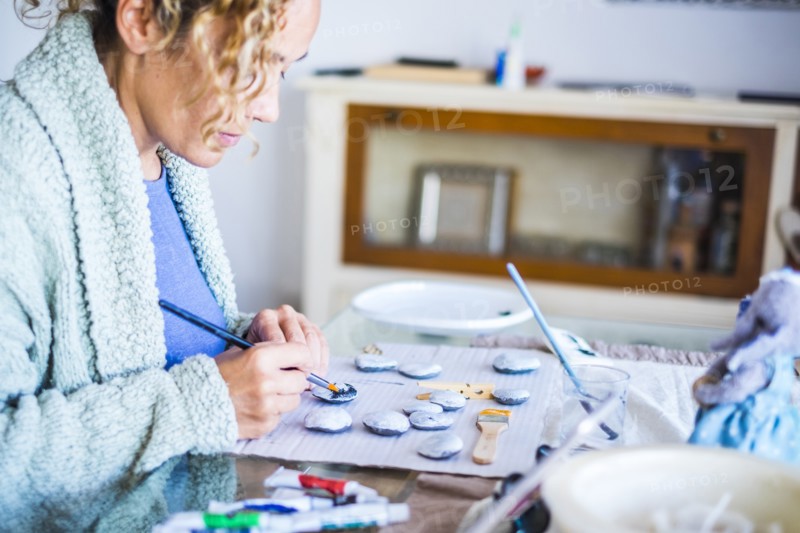 Woman painting stones at home