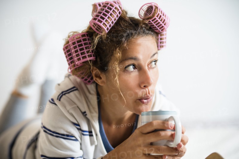Woman with hair curlers holding mug