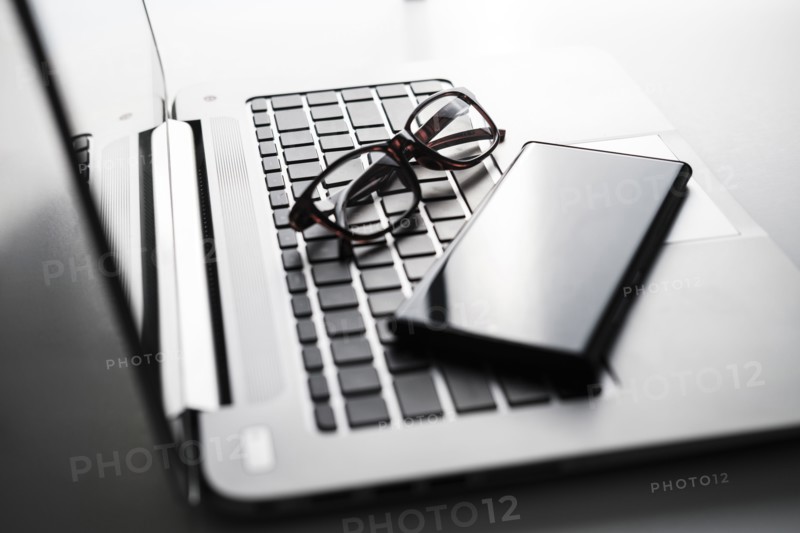 Smart phone and glasses on laptop keyboard