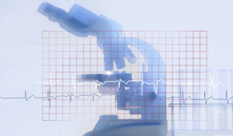 Silhouette of microscope behind electrocardiogram