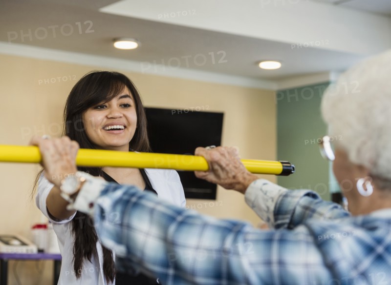 Smiling doctor helping senior woman hold pole
