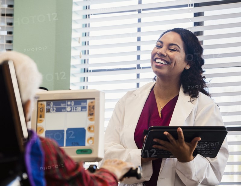Smiling doctor and senior man by machine monitor
