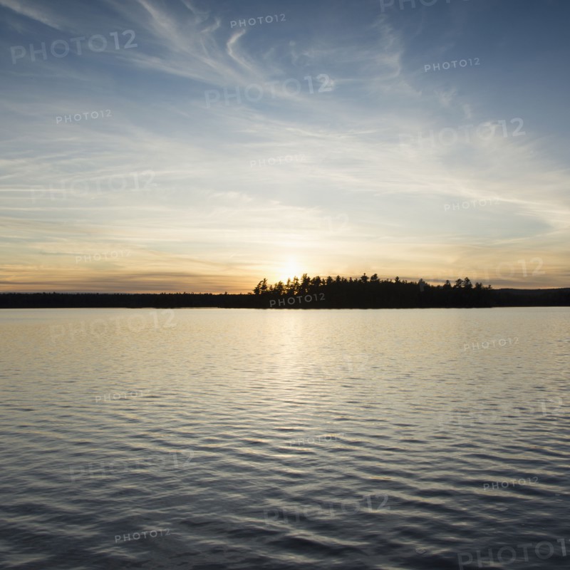 Silhouette of trees and lake at sunset