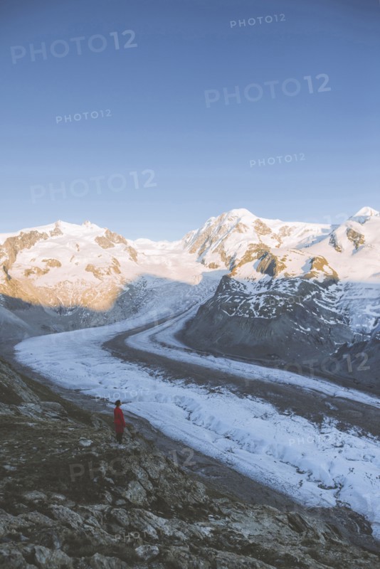 Woman standing on rock by Gorner Glacier in Valais, Switzerland