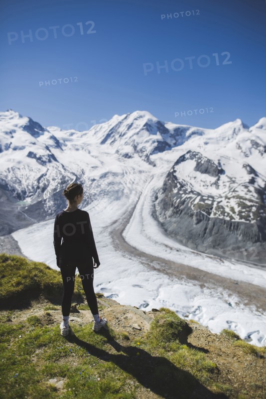 Woman standing on grass by Gorner Glacier in Valais, Switzerland
