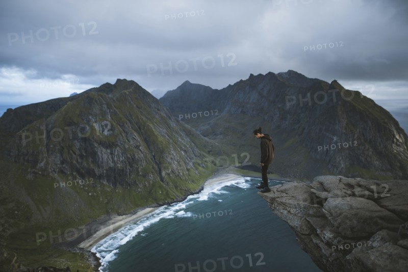 Man standing on cliff at Ryten mountain in Lofoten Islands, Norway