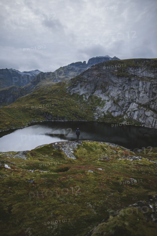 Man standing on rock by lake in Lofoten Islands, Norway