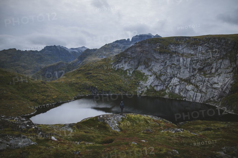Man standing on rock by lake in Lofoten Islands, Norway