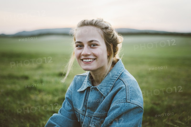 Smiling woman wearing denim jacket in field