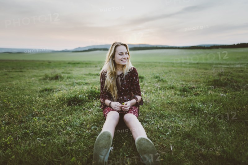 Smiling woman wearing dress sitting in field