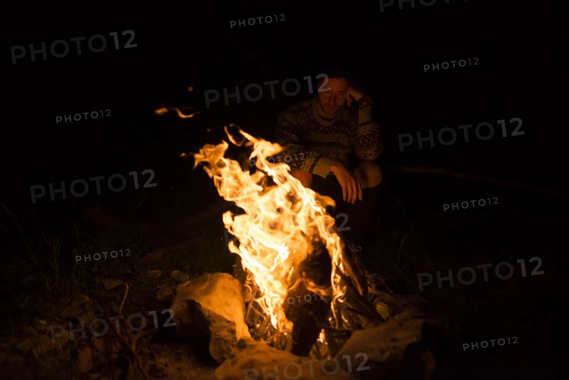 Man sitting by campfire at night