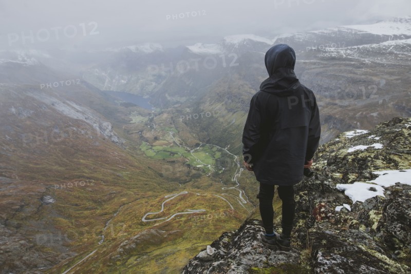Man holding camera on Dalsnibba mountain overlooking valley in Geiranger, Norway