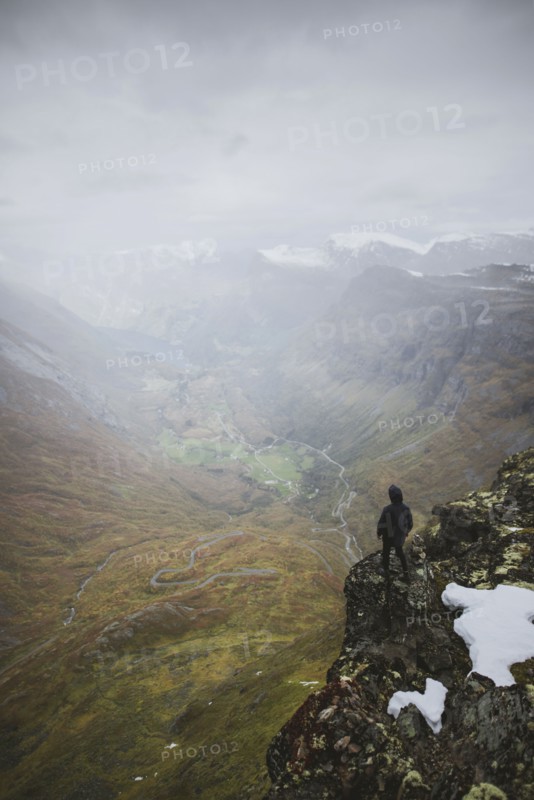 Man standing on Dalsnibba mountain overlooking valley in Geiranger, Norway