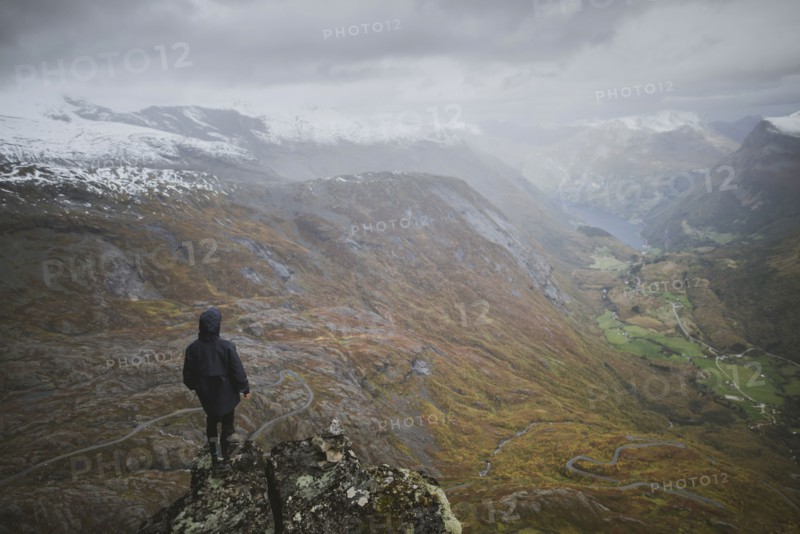 Man standing on Dalsnibba mountain overlooking valley in Geiranger, Norway