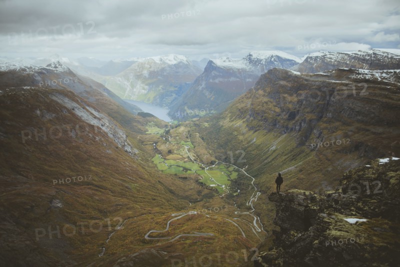 Man standing on Dalsnibba mountain overlooking valley in Geiranger, Norway