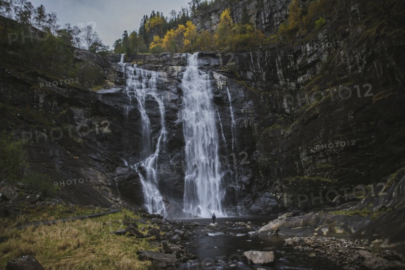 Person standing by Skjervefossen waterfall in Norway
