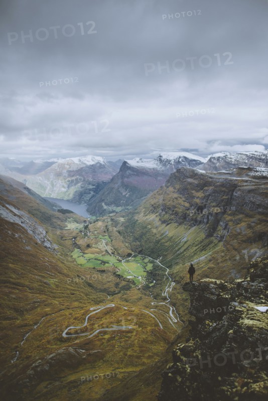 Man standing on Dalsnibba mountain overlooking valley in Geiranger, Norway