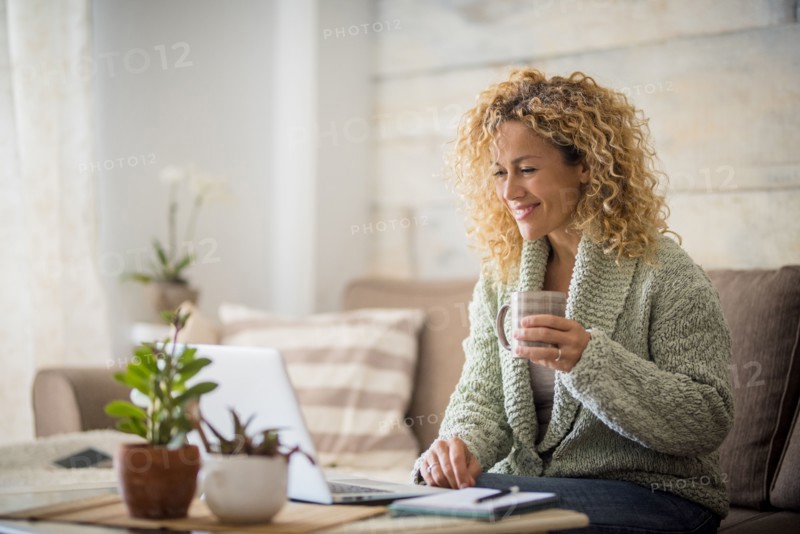 Smiling woman holding drink at laptop