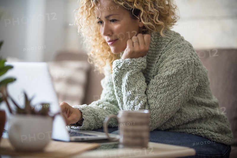Smiling woman working with laptop on sofa