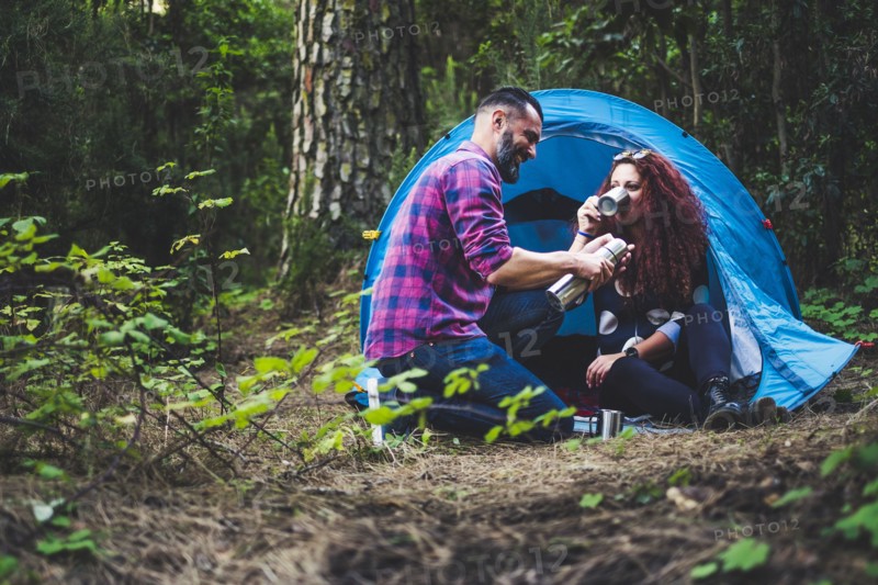 Smiling couple drinking by tent
