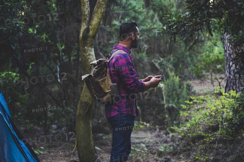 Man wearing backpack using smart phone in forest
