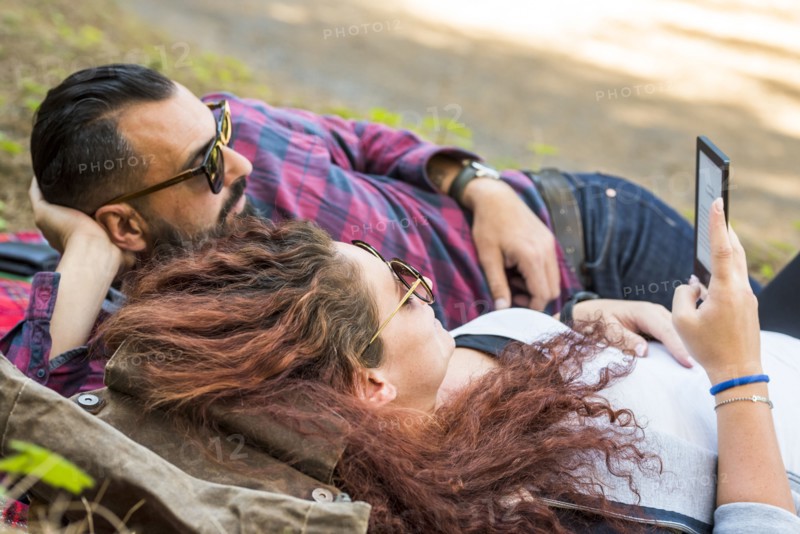 Couple lying on blanket using tablet