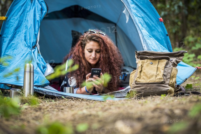 Woman lying in tent using smart phone