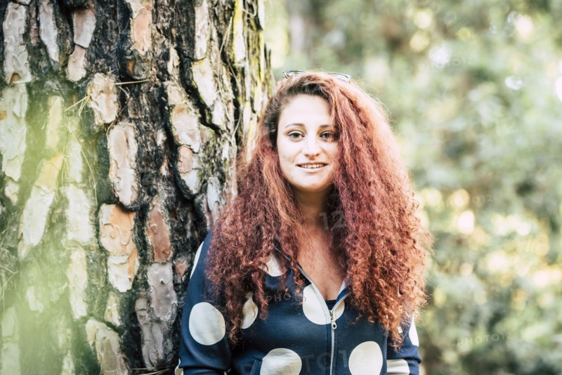 Smiling brown haired woman by tree