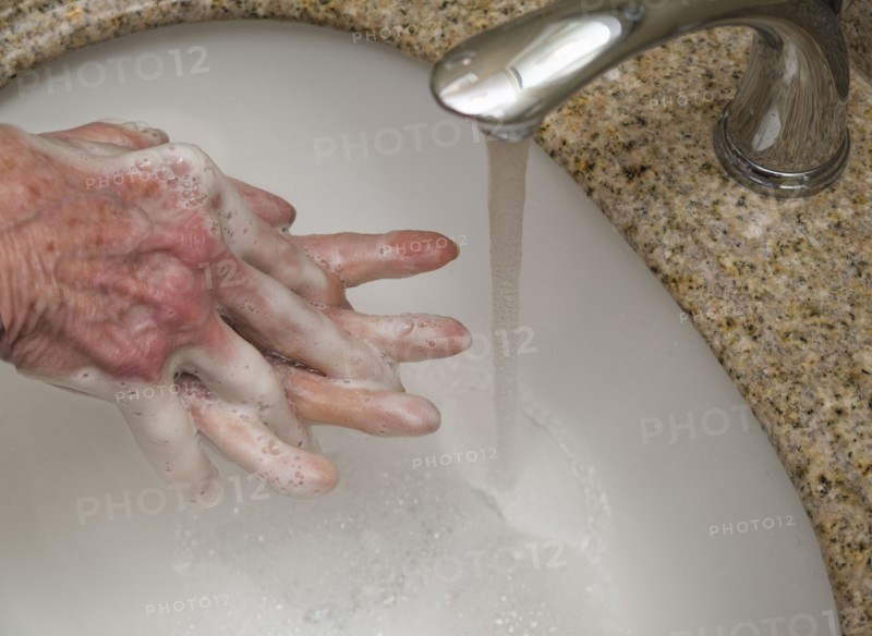 Senior woman washing hands in bathroom sink,  close-up of hands