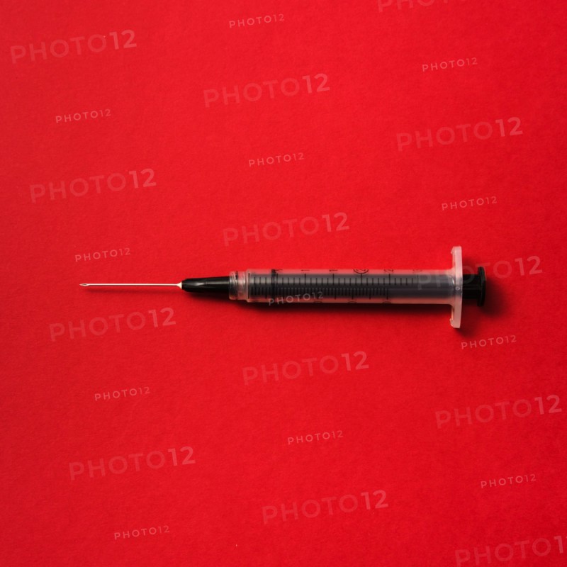 Syringe on red background