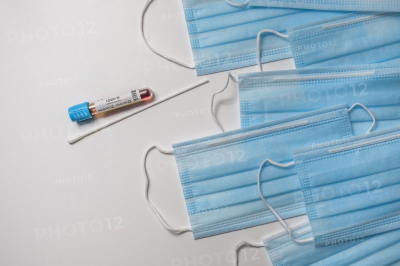 Blue medical masks and test tube with blood sample on white background