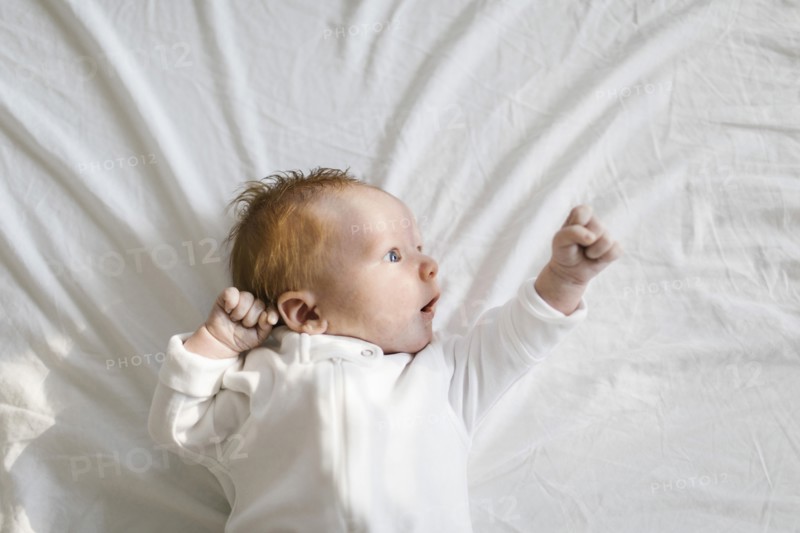 Baby boy (2-5 months) lying on bed